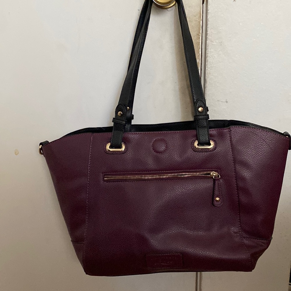 purple purse with zippers and pockets and an adjustable handle